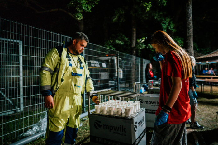 Pracownicy MPWiK napełniają kubeczki przy pomocy specjalnej maszyny napelniającej jednocześnie 25 kubeczków w 8 sekund